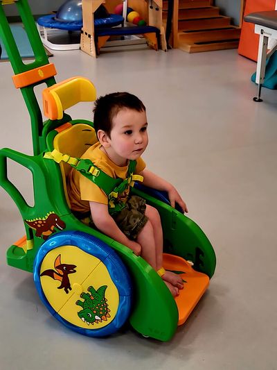 Boy uses Toddler Mobility Trainer with dinosaur designed wheels